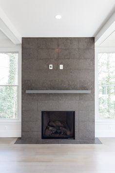 an empty living room with a fireplace and large windows