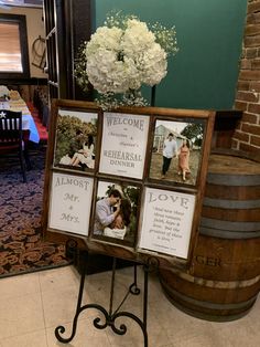 a wooden sign with pictures and flowers on it in front of a barrel filled with wine