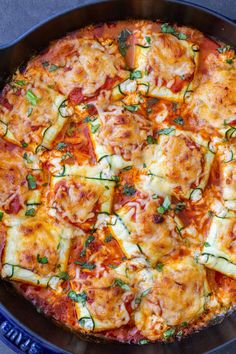 a pizza with zucchini and cheese in a blue pan on a table top