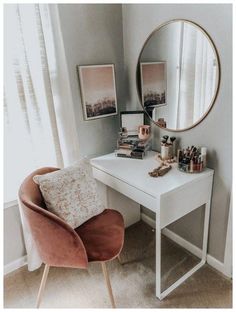 a white desk topped with a mirror and a pink chair next to it in front of a window