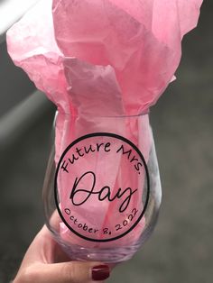 a person holding up a wine glass with pink tissue paper in it that says future mrs bag