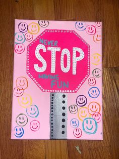 a stop sign painted on top of a pink canvas with embellishments and smiley faces