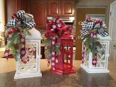 two red lanterns decorated with bows and pineconis are sitting on the kitchen counter