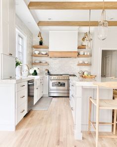 a kitchen with white cabinets and wood floors