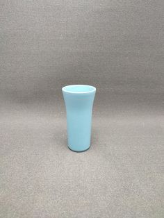 a light blue cup sitting on top of a table next to a wall and floor