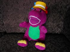 a purple stuffed animal with a hat on it's head sitting on a couch