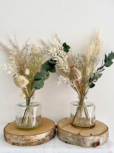 two vases with flowers are sitting on wood slices