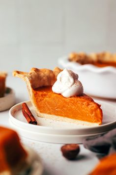 a slice of pumpkin pie with whipped cream on top and pecans in the background