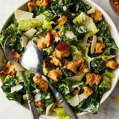 a white bowl filled with lettuce and croutons on top of a table