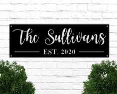 a black and white sign that says the sullivans est 2020 on it next to two potted trees