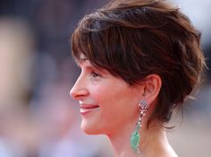 a close up of a person wearing earrings and looking off to the side with a smile on her face