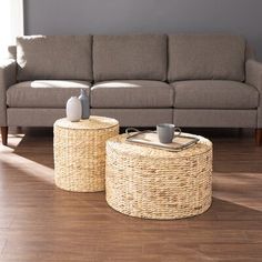 two wicker tables sitting on top of a wooden floor next to a gray couch