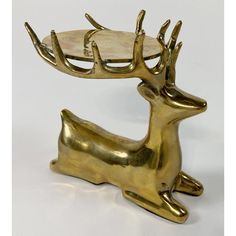 a brass deer figurine holding a tray on it's back with its legs spread out