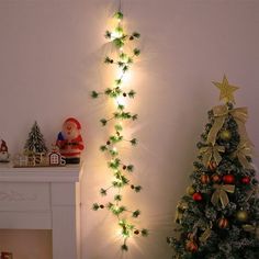 a christmas tree is next to a fireplace with lights on it and decorations around the fire place