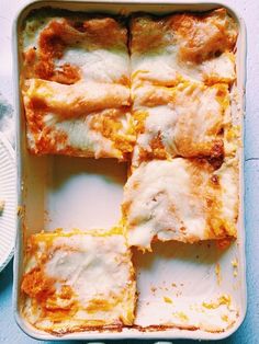 some food is in a white dish on a blue tablecloth and it looks like lasagna