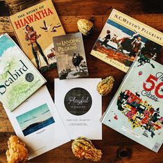 several books are laying on top of a wooden table next to cookies and other items