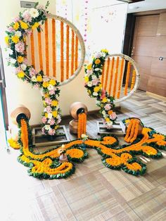 an arrangement of flowers arranged in front of two mirrors on the floor with other decorations