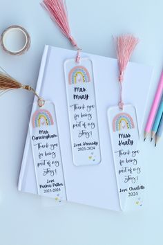 three personalized bookmarks with tassels and other items on the table next to them