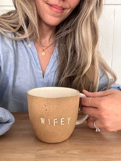 a woman sitting at a table with a coffee cup in front of her and the words wife written on it