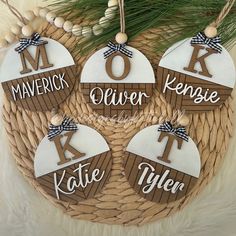 four personalized christmas ornament hanging from a wicker basket with pine needles