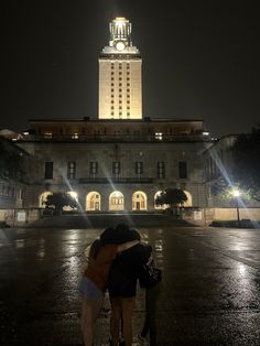 two people standing in front of a building at night