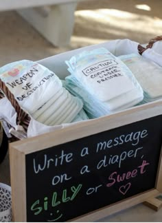 three diapers in a wooden box with writing on the side and an empty chalkboard attached to it