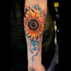 a sunflower tattoo on the left arm and shoulder with watercolor paint splatters all over it