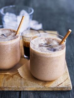 two glasses filled with drinks sitting on top of a wooden tray