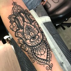 a black and white hamsa tattoo with an eye on it's side arm