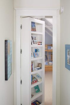 an open door leading into a room with bookshelves and pictures on the wall