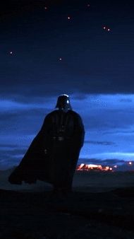 a man dressed as darth vader standing on top of a hill at night