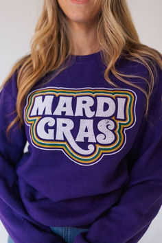 a woman wearing a purple sweatshirt with mardi gras on the front and side