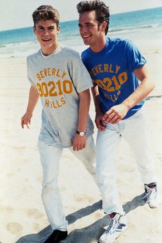 two young men standing next to each other on a beach