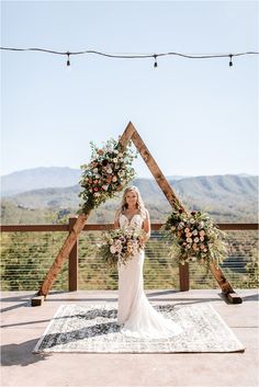 a woman standing in front of a wooden arch with flowers