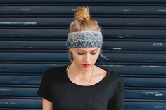 a woman wearing a headband and looking down at her cell phone while standing in front of a garage door