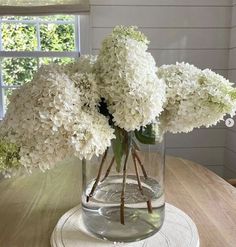 white flowers are in a glass vase on a table