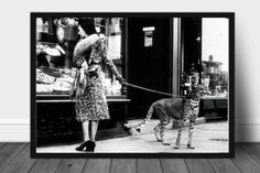 a woman walking a cheetah on a leash in front of a store window