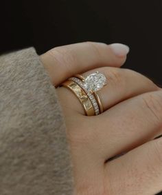 a woman's hand with two wedding rings on top of her finger and the ring has a diamond in it