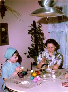 two women and a child are sitting at a table with easter eggs in front of them