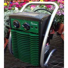 a green and black portable generator sitting on top of a table next to some flowers