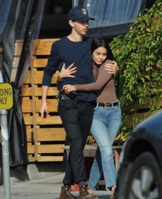 a man and woman are walking down the street with their arms wrapped around each other