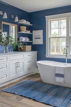 a white bath tub sitting next to a window in a blue and white bathroom on top of a wooden floor