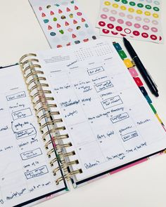 an open planner with stickers on it and a pen sitting next to the pages