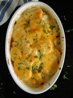 a casserole dish with cheese and parsley in it on a black surface