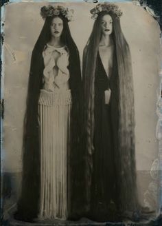 two women with long hair standing next to each other wearing headdress and veils