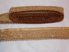 two pieces of gold sequinned fabric on a white tablecloth, one with beading and the other with beads