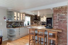 a kitchen with wooden flooring and white cabinets next to a brick wall in front of a window