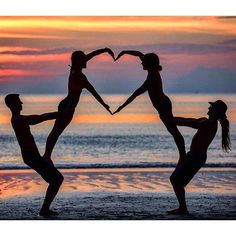 three people are doing yoga on the beach with their hands in the shape of a heart