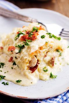 a white plate topped with mashed potatoes covered in bacon and garnished with parsley