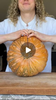 a woman holding a pumpkin on top of a wooden table